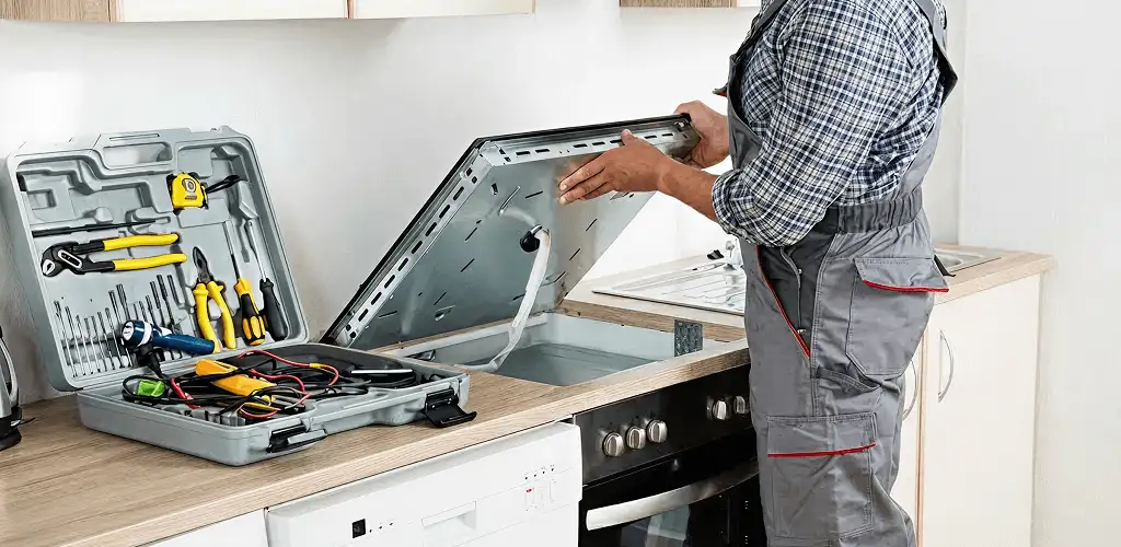 Handyman repairing a cooktop and checking wiring connections in Bellevue, WA