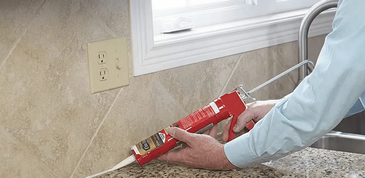 Handyman applying caulk along a kitchen backsplash and countertop seam in Bellevue, WA