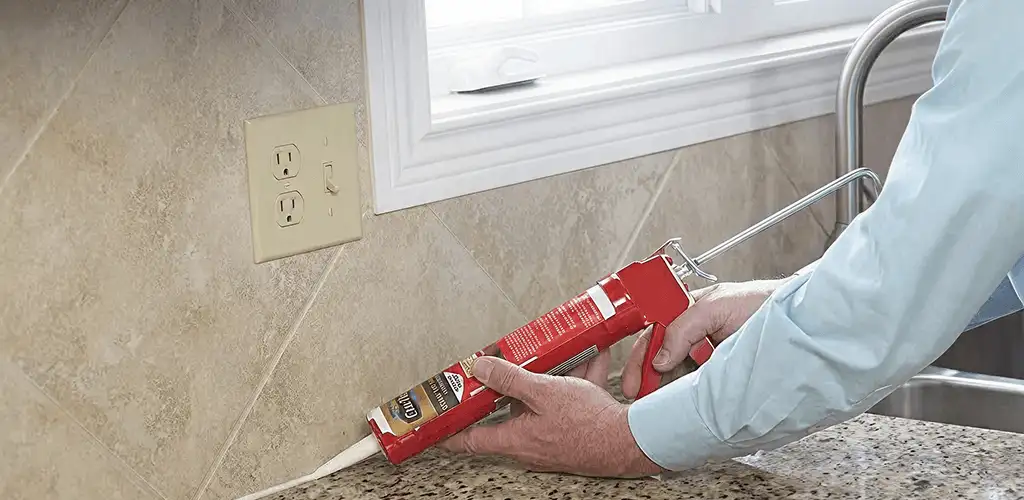 Handyman applying caulk along a kitchen backsplash and countertop seam in Bellevue, WA