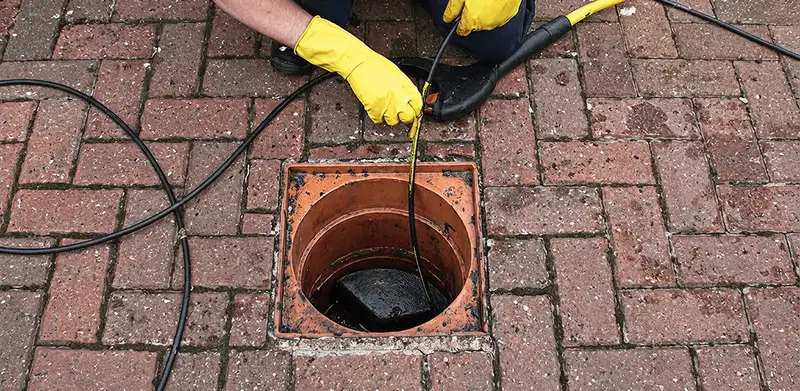 Drain cleaning technician using a drain snake to clear a clogged drain in Bellevue, WA