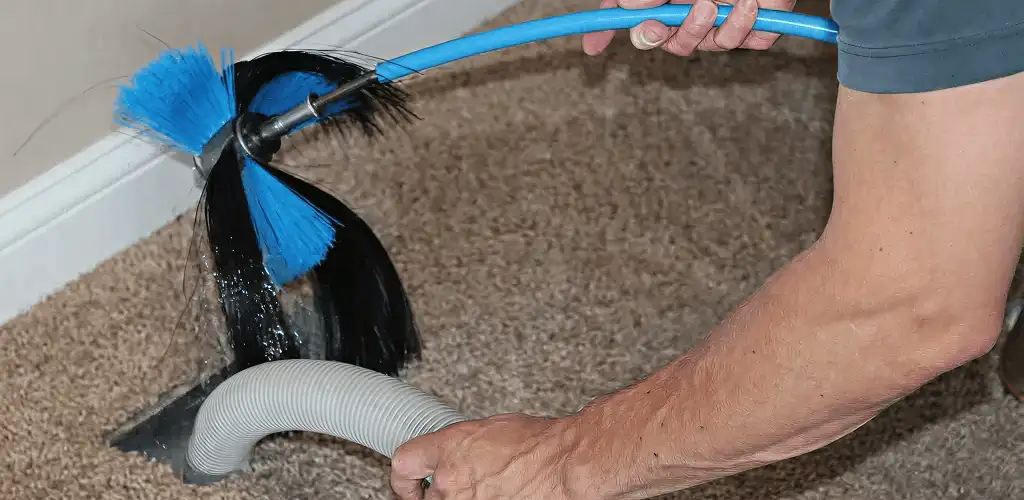 Dryer vent cleaning technician brushing lint from a vent line in Bellevue, WA