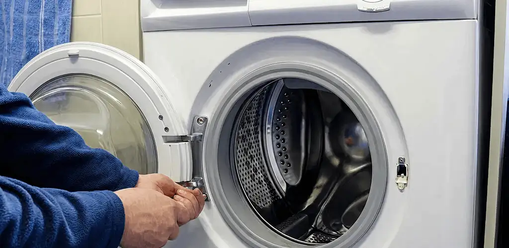 Washing machine repair handyman checking a front-load washer door and latch in Bellevue, WA