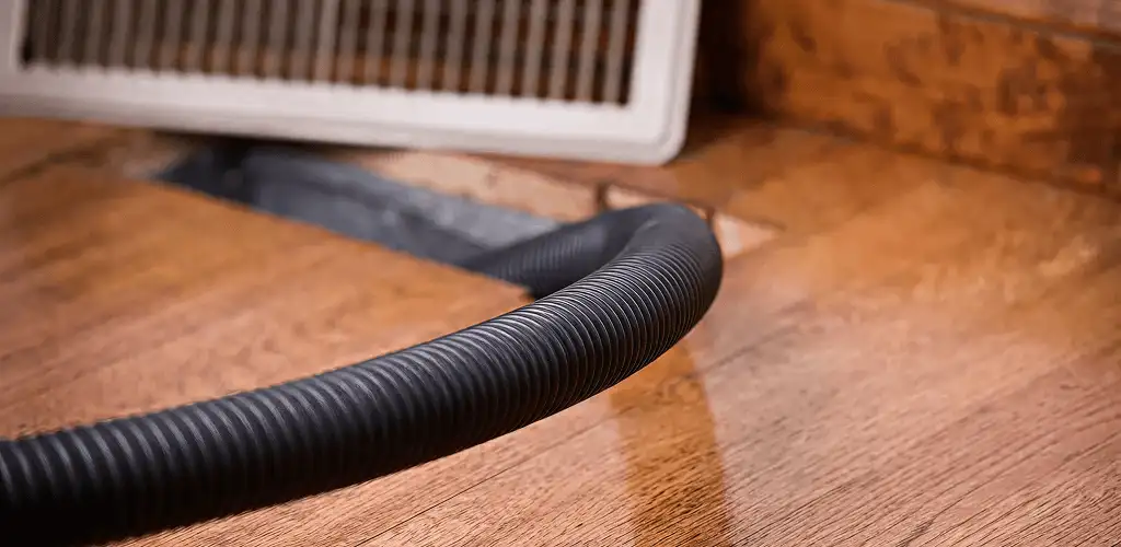 Air duct cleaning hose inserted into a floor vent for ductwork cleaning in Bellevue, WA