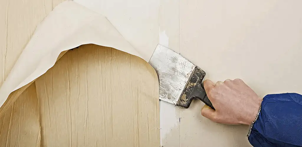 Handyman removing wallpaper with a scraper for wall preparation in Bellevue, WA