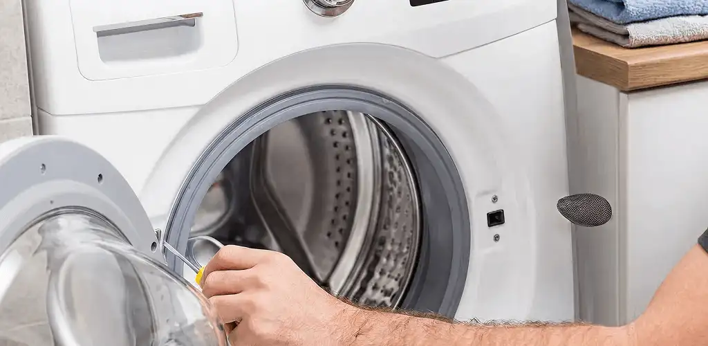 Handyman repairing a front-load washing machine and inspecting the drum in Bellevue, WA
