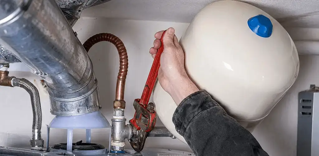 Water heater repair technician tightening plumbing connections near a tank unit in Bellevue, WA
